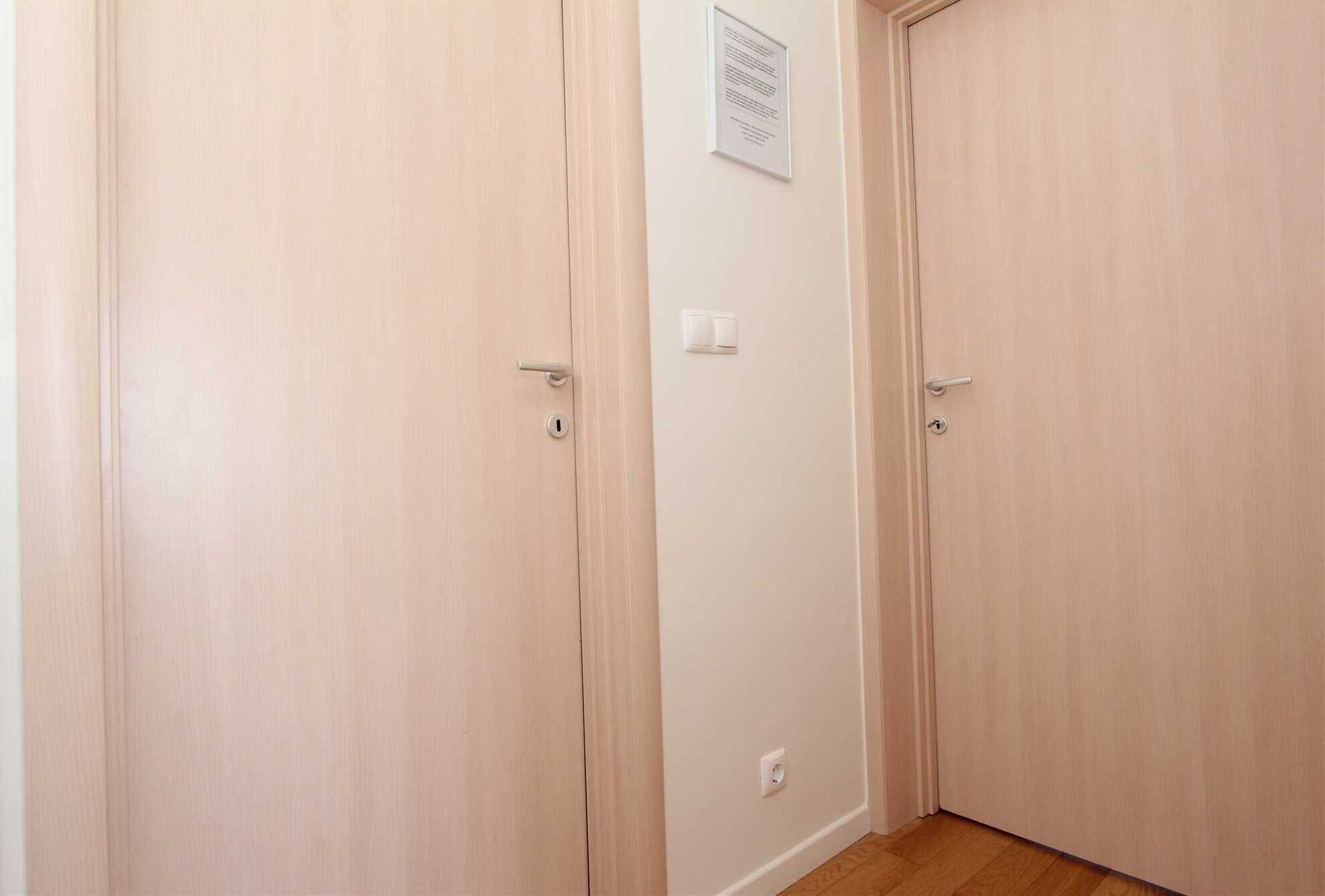 Une pièce dotée de deux portes en bois, d’un interrupteur et d’une petite prise électrique au mur.