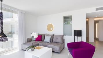Una sala de estar moderna con un sofá gris, una mesa de centro blanca y un sillón morado.