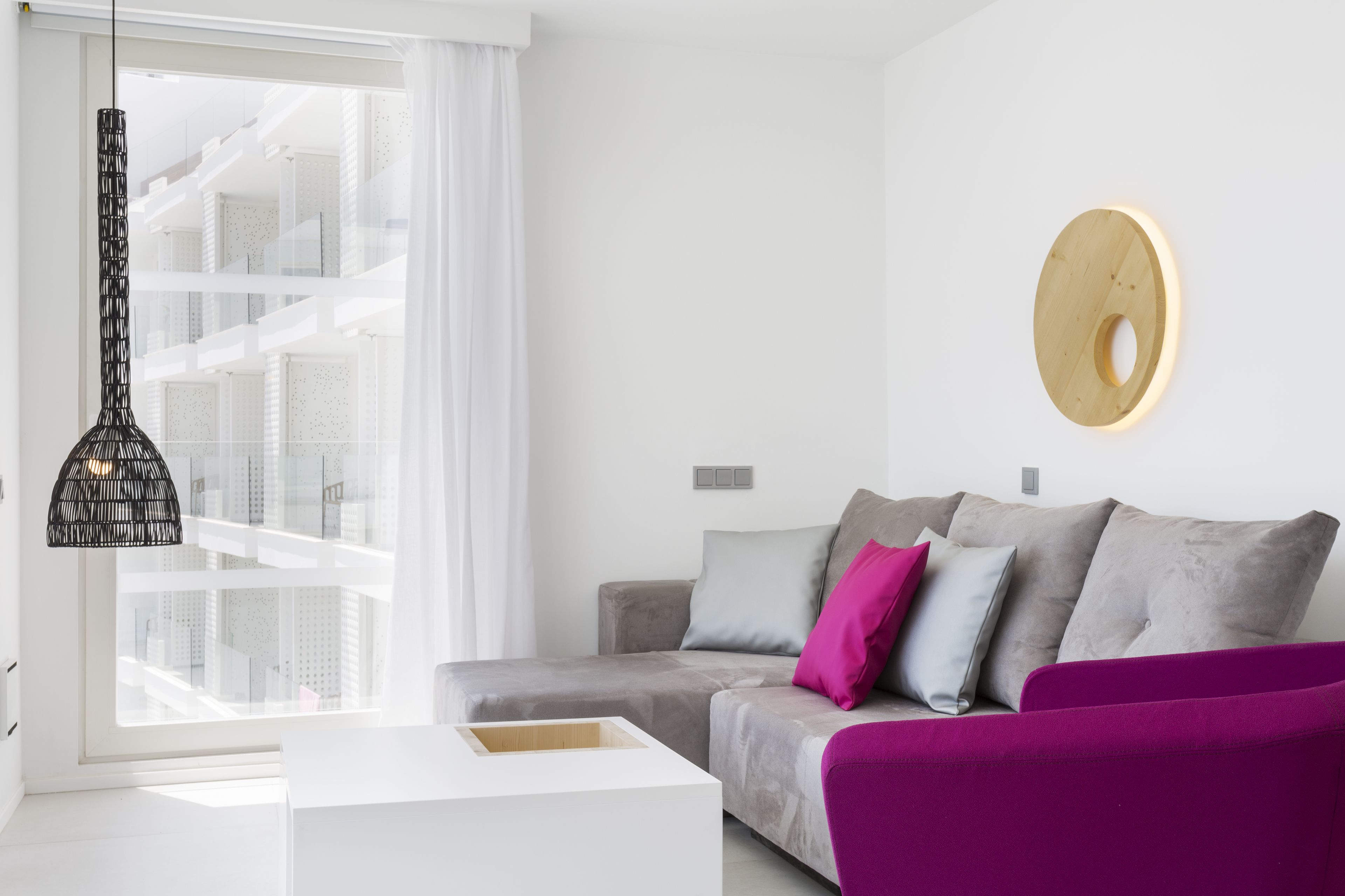 A modern living room with a grey sofa, a white coffee table, and a purple armchair.