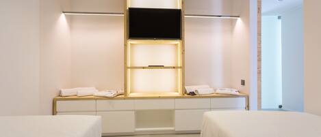 A hotel room with a bed, a TV mounted on a wall, and a bedside table with a towel.
