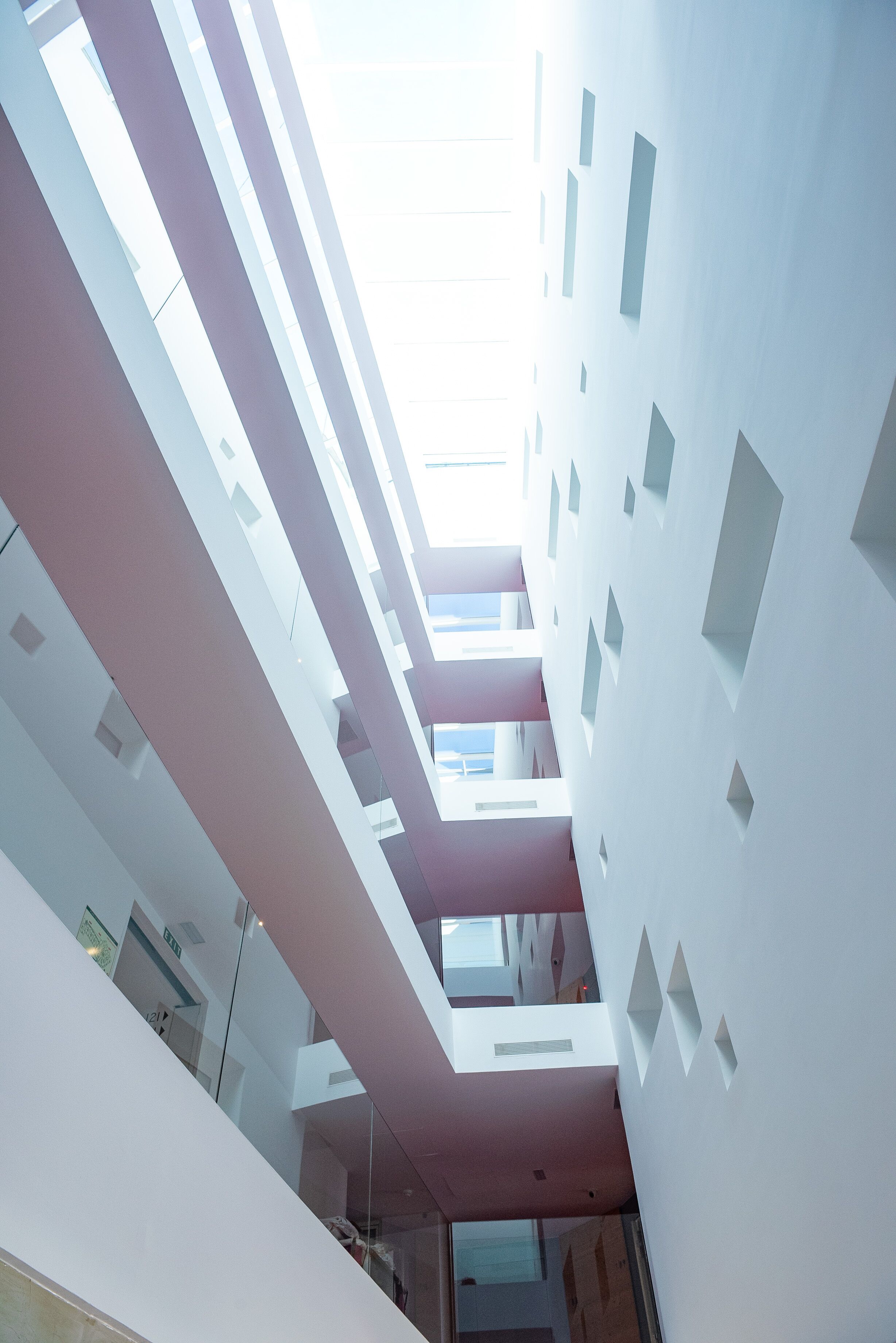 Un interior moderno con techo alto, diseños geométricos en las paredes y un espacio central abierto.