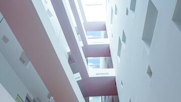 Un interior moderno con techo alto, diseños geométricos en las paredes y un espacio central abierto.