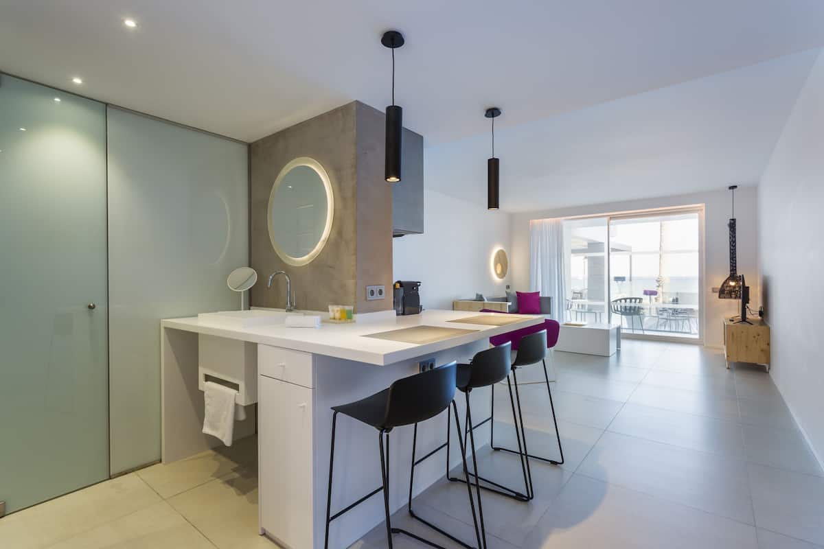 Een moderne keuken met een centraal eiland, barkrukken en hanglampen.