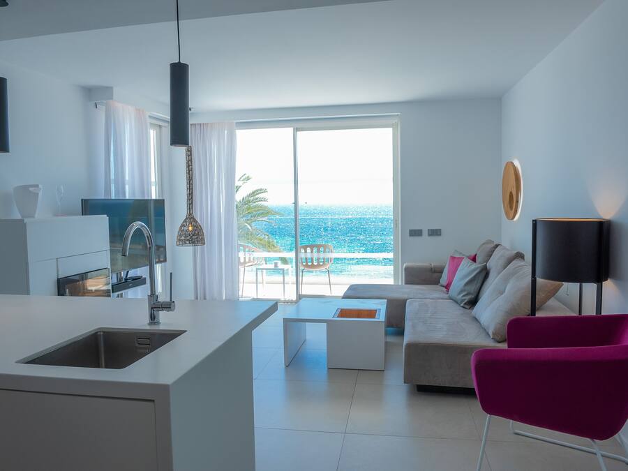 Una sala de estar moderna con un sofá, una mesita de centro y una vista luminosa al mar.
