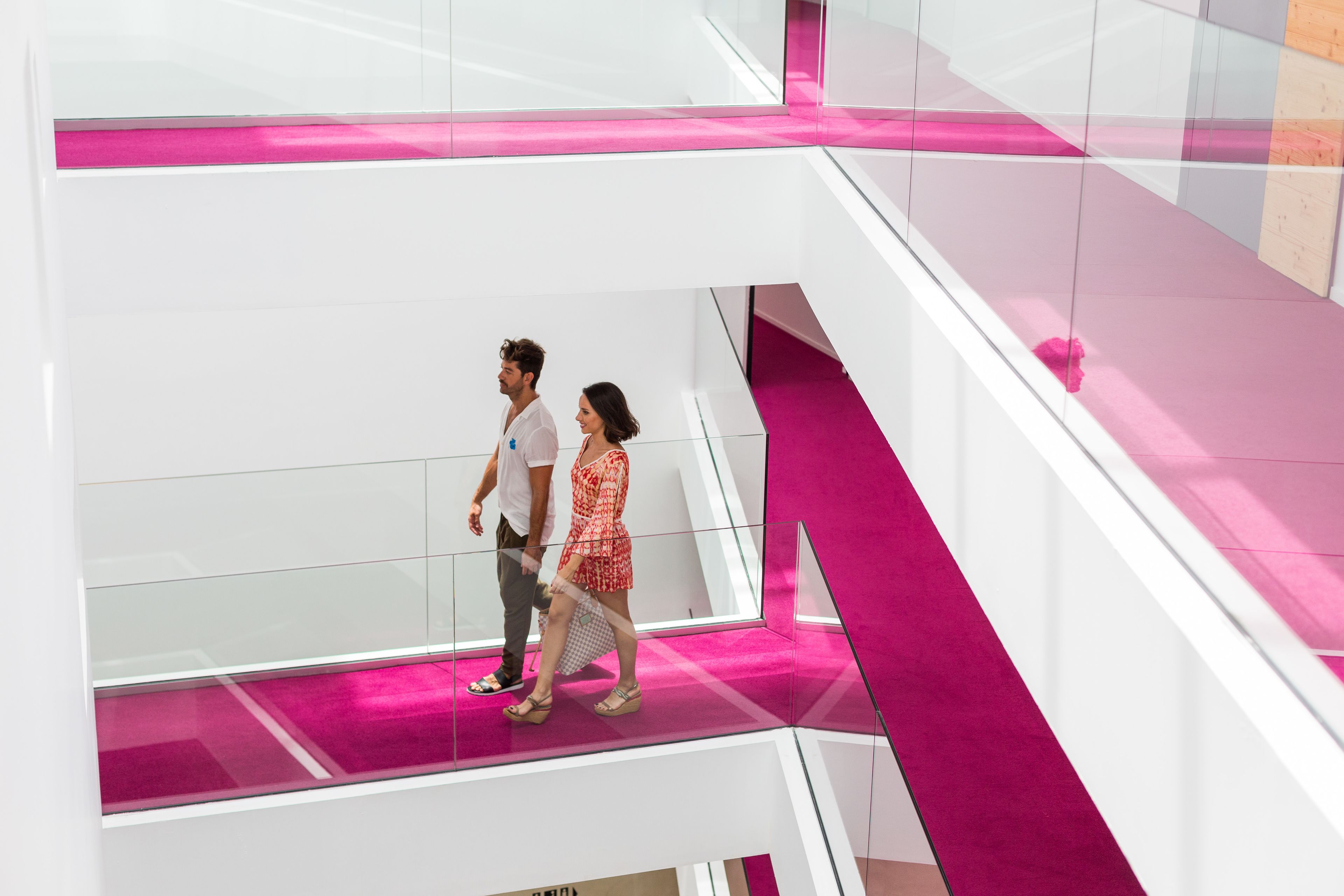 A modern interior with a glass railing and a pink accent wall.