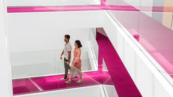 A modern interior with a glass railing and a pink accent wall.