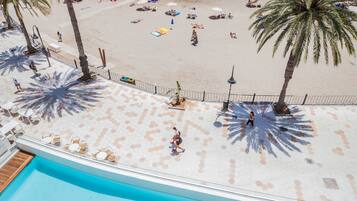 Relax by the pool overlooking the adjacent beach, where lounge chairs and palm trees await.