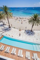 Vista a la piscina con una playa y el océano al fondo.
