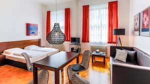 A hotel room with a bed, a dining table, a sofa, and a TV.