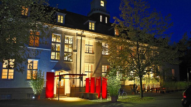 A building with a tower, large windows, and a well-lit entrance.