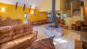 A spacious living area with a leather sofa, wooden chairs, a fireplace, and a staircase.