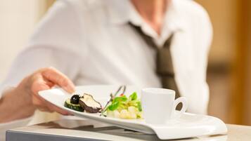 A person holding a white plate with food and a white cup on a tray.