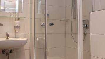 A modern bathroom with a glass-enclosed shower, a white sink, and a toilet.
