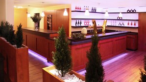 A bar area with wooden counters, a variety of bottles, and hanging pendant lights. - Landhaus Jaegerkrug (Paderborn)