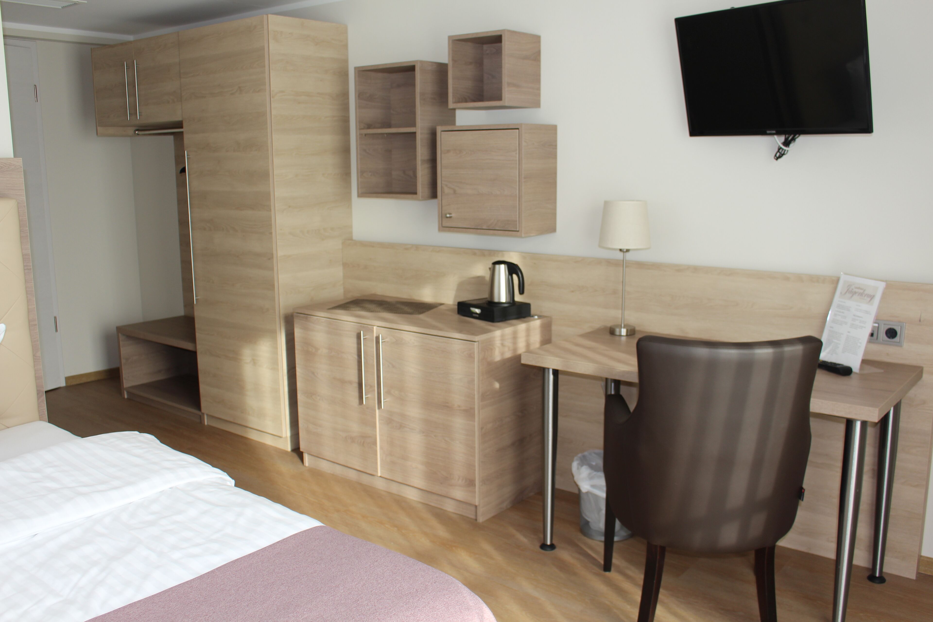 Una habitación de hotel con cama, escritorio, silla, televisión y minibar.