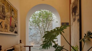 A hallway with a bench, a large potted plant, and a framed picture on the wall. - Casa Carmen Morelos (Oaxaca)