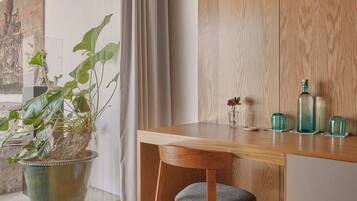 Una habitación moderna con un escritorio de madera, una silla, una planta en maceta y vistas por la ventana.