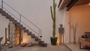 A modern interior with a concrete staircase, a large cactus, and minimalist decor. - Casa Carmen Morelos (Oaxaca)