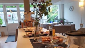 Ein langer Esstisch, gedeckt mit Speisen, Blumen in einer Vase und verschiedenen Gewürzen.