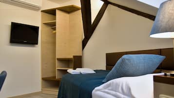 A bedroom with a bed, a TV mounted on the wall, and a wooden shelving unit.