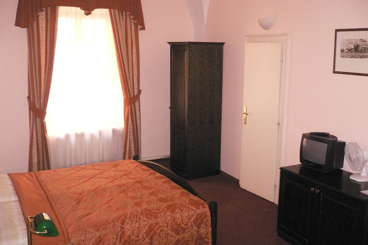 A hotel room with a bed, a wardrobe, a television, and a door.