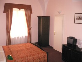 Quarto de hotel com uma cama, guarda-roupa, televisão e uma porta.