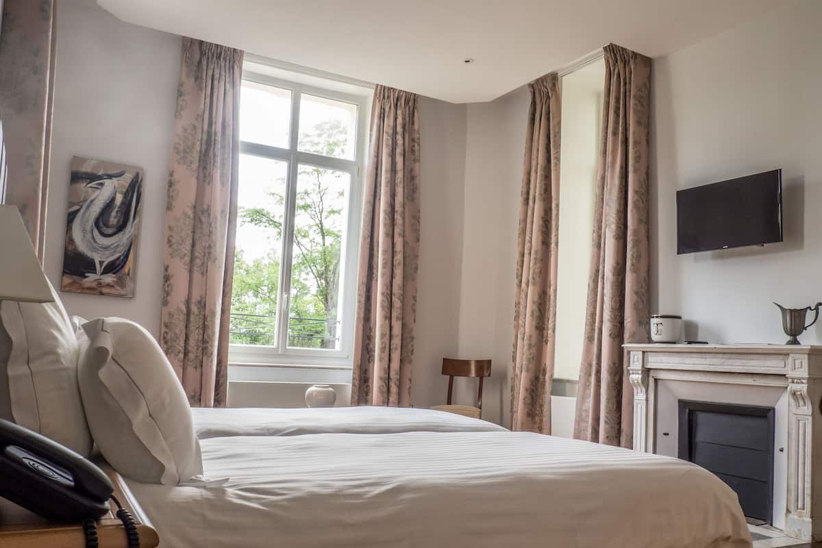 Une chambre d’hôtel avec un lit, une télévision, une cheminée et une fenêtre avec des rideaux.