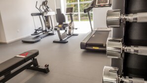 A gym with exercise equipment including treadmills, stationary bikes, and weight machines. - Hôtel Château de la Marlière (Fourmies)