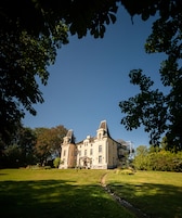 A large, historic building with a symmetrical facade, multiple chimneys, and a central entrance.
