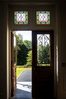 A doorway with a wooden door and a metal gate, leading to a garden with a paved path.