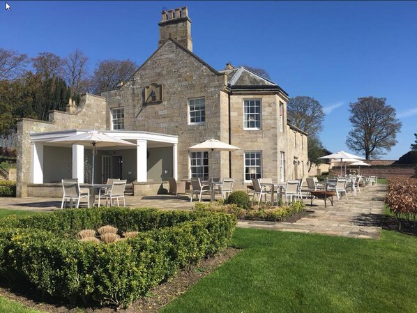 A stone building with a covered patio area, outdoor seating, and a well-maintained garden.