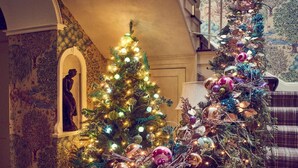 Een statige trap met een versierde kerstboom, versierd met lichtjes en decoraties.