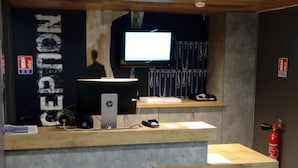 Un mostrador de recepción con una computadora, un televisor de pantalla plana y un extintor.