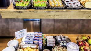 Un bufé con diversas opciones de comida, como frutas, yogures y aperitivos envasados.