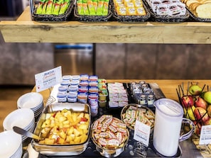 Un buffet proposant une variété d’aliments, notamment des fruits, des yaourts et des en-cas emballés.