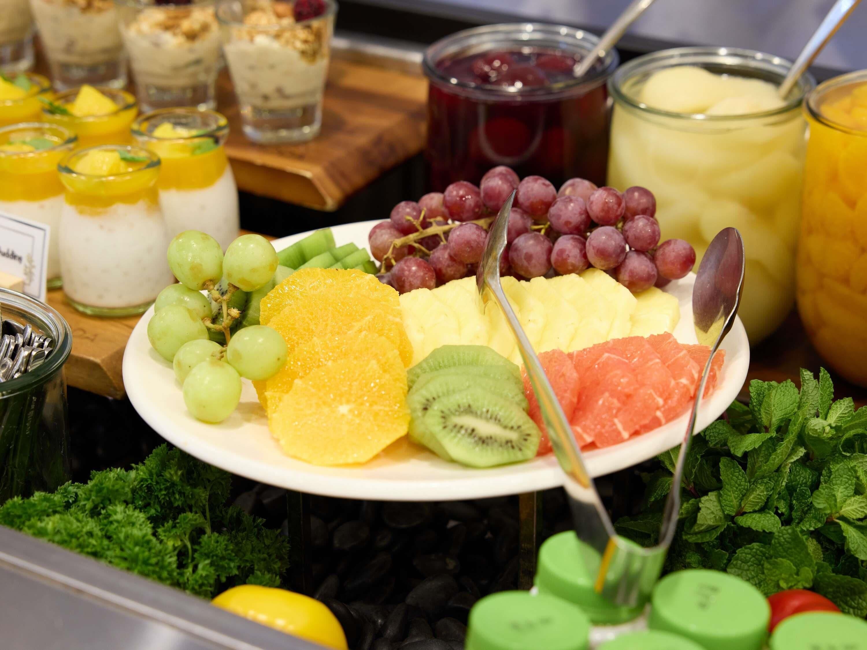 Un assortiment de fruits comprenant des raisins, des kiwis, des oranges et de la pastèque.