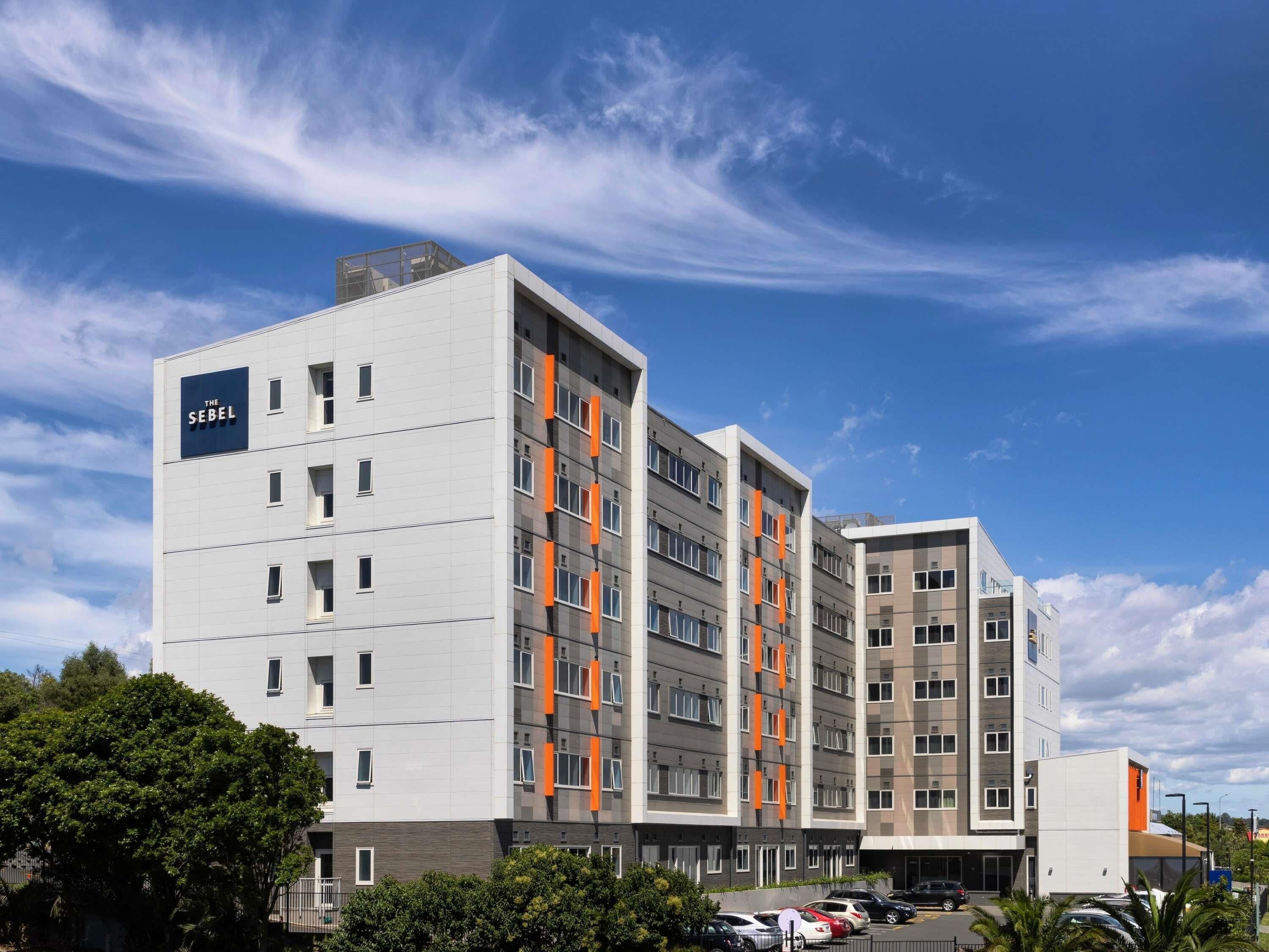 A multi-story hotel with a modern design, featuring a prominent sign on the left side.