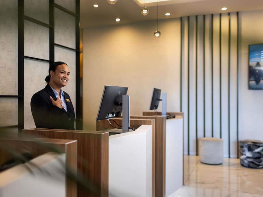 Una recepción con un ordenador, mostrador de madera y diseño de interiores moderno.