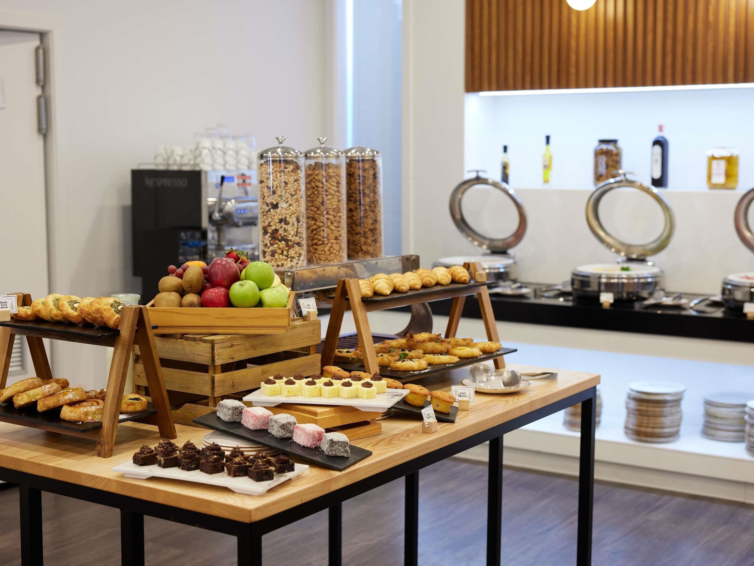 A buffet with various pastries, fruits, and condiments.