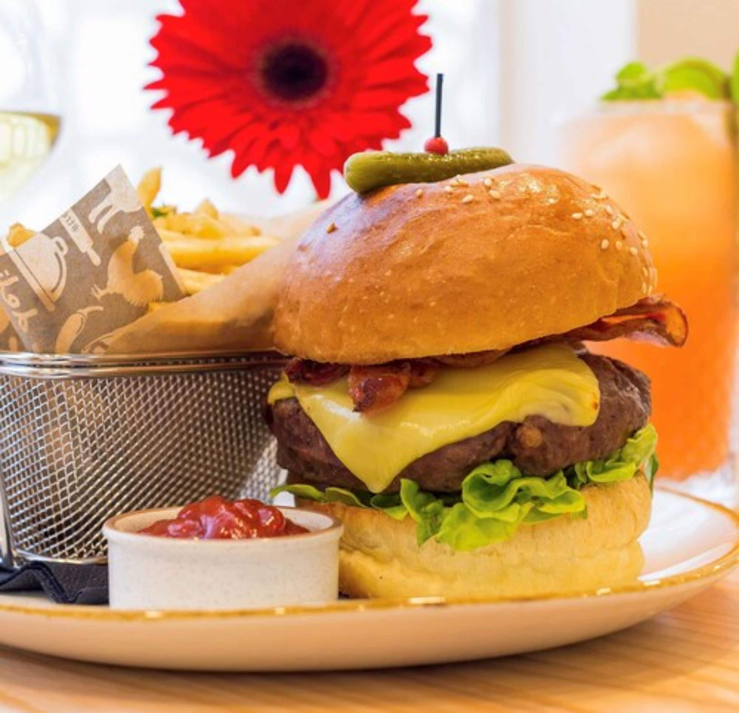 A burger with cheese, lettuce, and bacon, served with fries and ketchup.