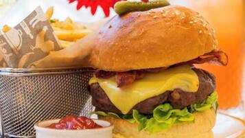 A burger with cheese, lettuce, and bacon, served with fries and ketchup.
