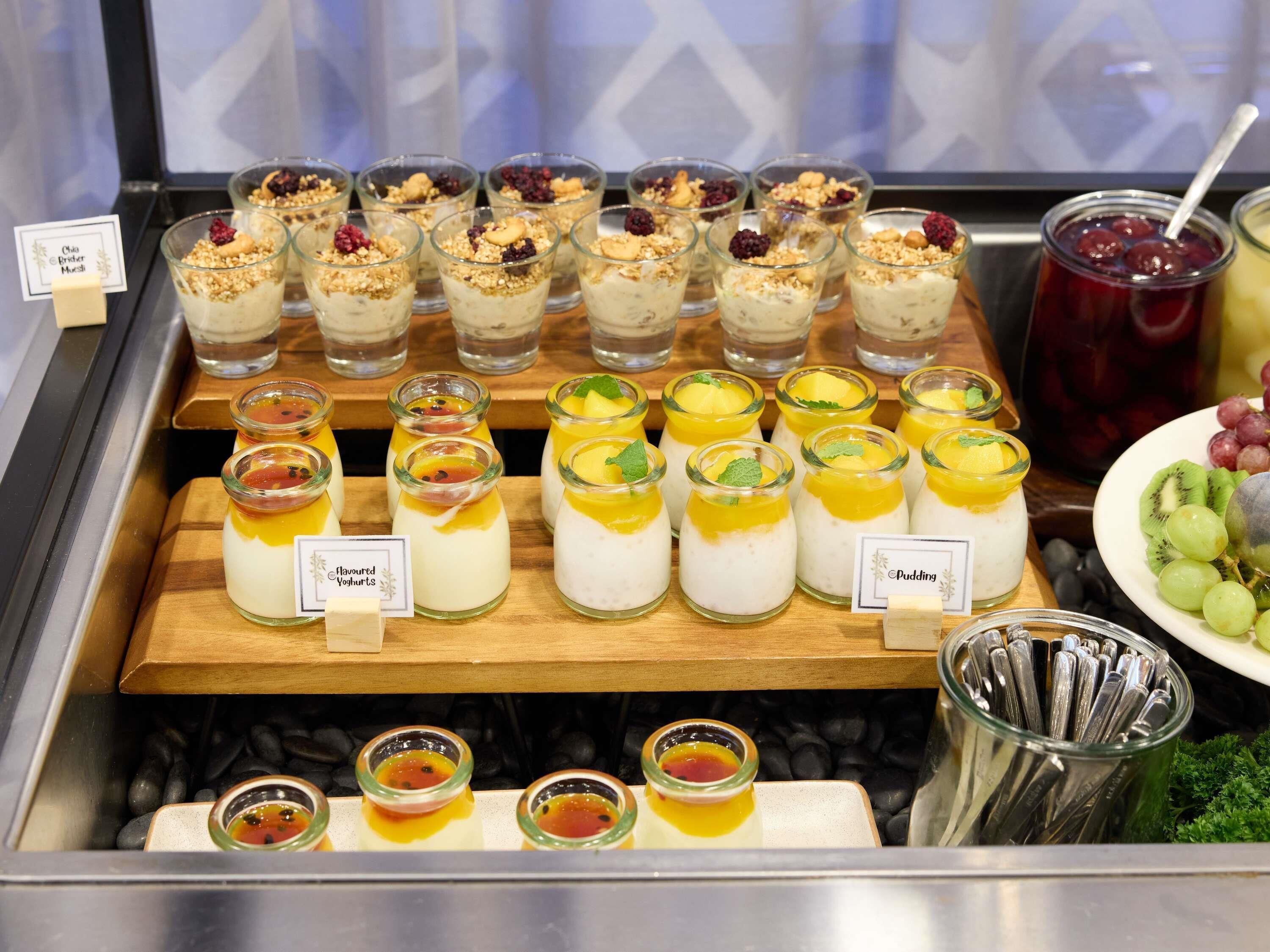 A dessert display with various fruit-topped yogurts and puddings.