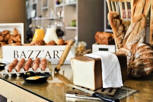 Un bufé de desayuno con varios pasteles, una hogaza de pan y un cartel que dice "BAZZ'ART".