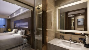 Une chambre d’hôtel moderne dotée d’un grand lit, d’une douche en verre, d’un lavabo en marbre et d’un grand miroir.