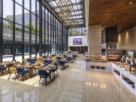 A spacious restaurant with high ceilings, large windows, and a central bar area.
