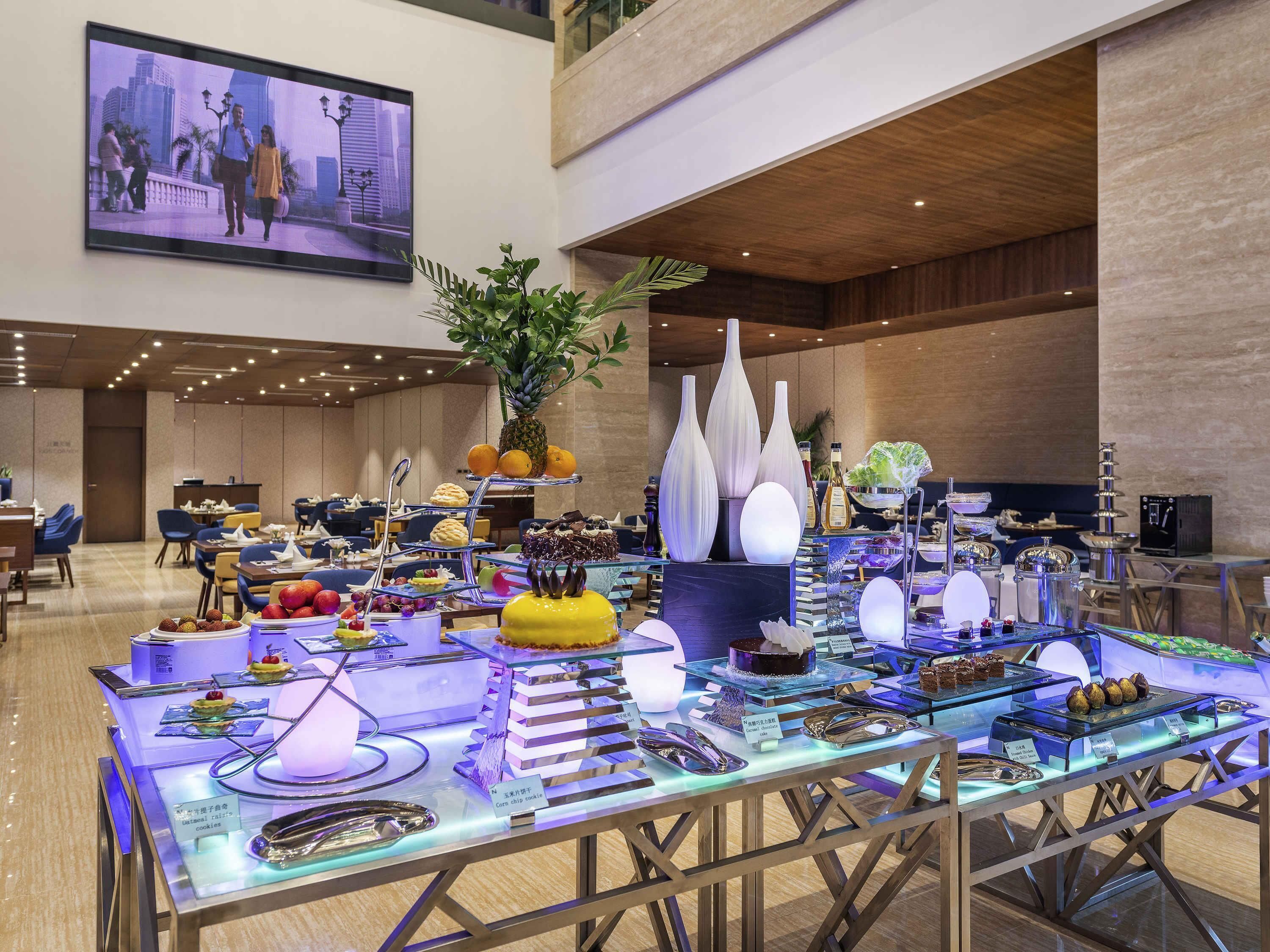 Vestíbulo de hotel con zona de buffet que presenta diversos alimentos y jarrones decorativos.