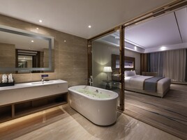 Un baño de hotel moderno con bañera, tocador y un espejo grande.