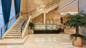 Un intérieur moderne agrémenté d’un escalier, d’un lustre et d’une vitrine contenant divers objets.