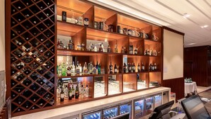 A bar area with multiple shelves of liquor bottles, a wine rack, and a cash register. - Novotel Ulaanbaatar (Ulaanbaatar)