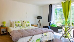 A bedroom with a bed, a nightstand, a lamp, a chair, and a table. - Les Jardins de l'Ermitage (Les Salles-sur-Verdon)